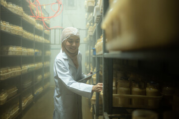 Young asian muslim female scientist doing research at a mushroom factory, examining mushroom...