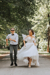Fototapeta na wymiar A wedding couple, a happy bride and groom are running in the park to the place of the wedding ceremony. Wedding concept