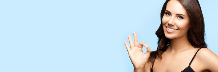 Portrait of smiling beautiful woman in black casual tank top, making ok okay hand sign gesture,...