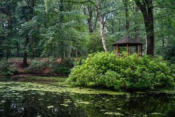 a wooden house in a park on a bridge above the water in a green landscape