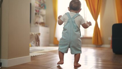 baby first steps. baby goes to her father at window learns to walk to take first steps. happy family kid dream concept. dad calls son baby first steps indoors. happy family indoors concept lifestyle