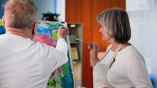 retired hobby, elderly talented artists draw creative modern painting with paint and brush on canvas using easel