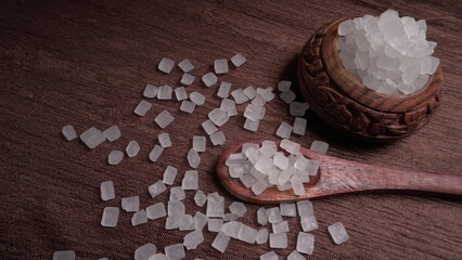 Wooden Spoon with white sugar on the dark background.