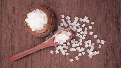 Wooden Spoon with white sugar on the dark background.