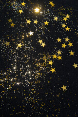 gold star confetti and glitter on a black glitter background 