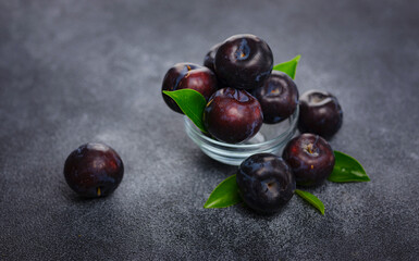 Sweet plums on dark background. Fresh blue plums with leaves. Food fruit Background. Summer postcard. Harvesting in garden, Harvest of plum