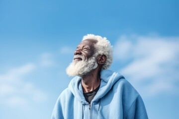 Medium shot portrait photography of a glad old man wearing a stylish hoodie against a sky-blue background. With generative AI technology