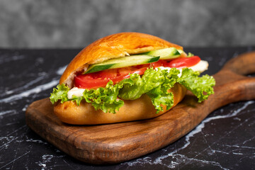 Sandwich with cheese, tomato, cucumber and lettuce. Delicious sandwich on wood serving board