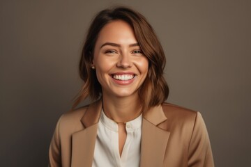 Close-up portrait photography of a grinning girl in her 30s wearing a sleek suit against a warm taupe background. With generative AI technology