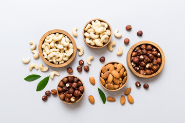 Assortment of nuts in wooden bowl on colored table. Cashew, hazelnuts, walnuts, almonds. Mix of nuts Top view with copy space