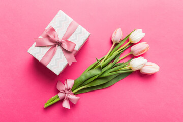 Pink tulips flowers and gift or present box on colored table background. Mothers Day, Birthday,...
