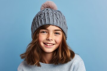Headshot portrait photography of a grinning kid female wearing a warm beanie against a periwinkle blue background. With generative AI technology