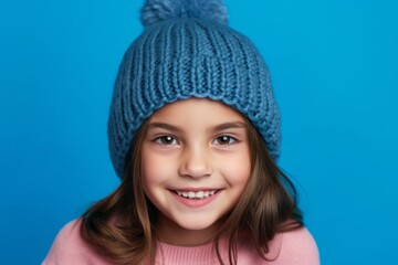 Headshot portrait photography of a grinning kid female wearing a warm beanie against a periwinkle blue background. With generative AI technology