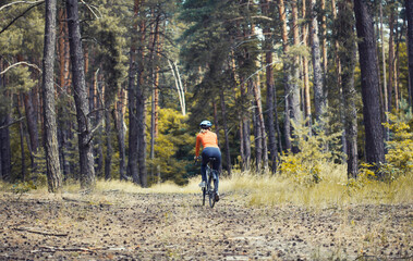 Obraz premium woman cyclist rides in the forest on a mountain bike.