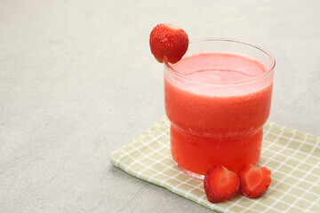 Glass of strawberry juice with strawberry fruit on wooden table
