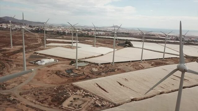 aerial shot through wind turbines in a wind farm and in a desert environment