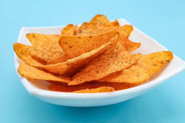 nachos on a plate on a blue background with copy space