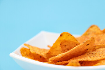 nachos on a plate on a blue background with copy space