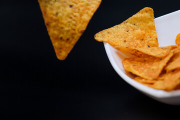 mexican nachos in a bowl on black background with copy space