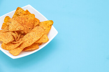 nachos on a plate on a blue background with copy space