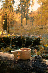 wooden cup with tea on stump in autumn forest, natural abstract background. Traditional Finnish mug...