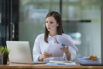 A businesswoman and accountant read reports for information, financial data, or analysis....