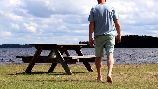 Mora, Sweden A man walks to a picnic table in a park on the shore of Lake Siljan on a summer day. 