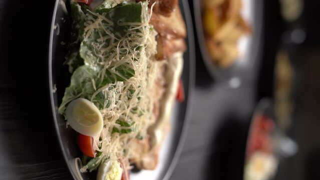 Traditional Caesar salad with meat chicken pieces cherry tomatoes croutons served on dark table, close-up
