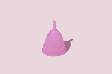 Pink reusable silicone menstrual cup on pink background. Concept of feminine hygiene, gynecology and health