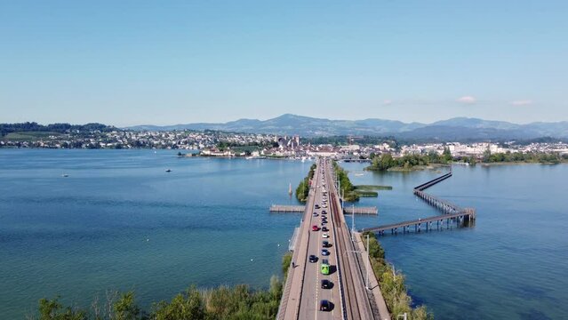 Rapperswil, Switzerland: Aerial drone footage of the bridge over Lake Zurich toward the rapperswil-Jona city in canton Saint Gallen on the sunny summer day with a forward tilt down motion. 