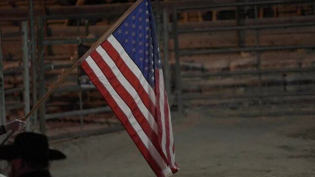 This video shows an American flag blowing in the wind in slow motion at a rodeo event.