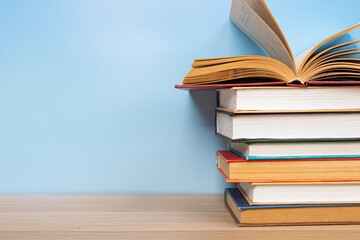 Composition with vintage old hardback books, diary and open book whith old pages on wooden table and blue background. Books stacking. Back to school. Copy Space. Education background.