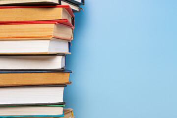 Stack of books in the colored cover lay on blue backround. Education learning concept