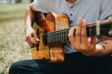 Obraz premium detail photograph of young man playing acoustic guitar outdoors. Concept of people, musicians and hobbies.