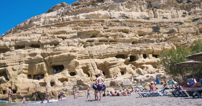 Matala, Greece - 18 june 2023: turists visit towards the rocks with caves in which hippies used to live, Matala beach the island of Crete in Greece