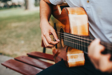 detail photograph of young man playing acoustic guitar outdoors. Concept of people, musicians and hobbies. - obrazy, fototapety, plakaty