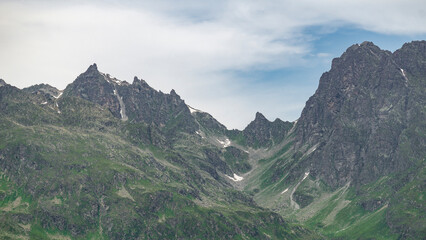 Steinige, steile Berge zwischen Tirol und Vorarlberg, Österreich, mit Schnee im Sommer und grünen Weiden aus dreistufiger Almwirtschaft. Wunderschönes Gebiet zum Klettern und Wandern, Erholung pur 
