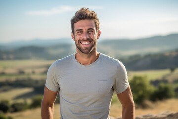 Sports portrait photography of a happy boy in his 30s wearing a casual t-shirt against a rolling hills background. With generative AI technology