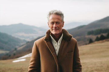 Lifestyle portrait photography of a tender mature man wearing a cozy winter coat against a rolling hills background. With generative AI technology