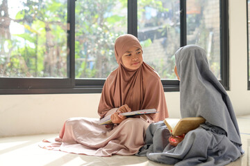 Two Muslim kid girls having conversation after reading Quran inside the mosque.
