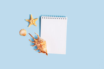 To do list or blank notebook with set of starfish, sea shell on blue background. Travel, summer vacation or weekend, packing plan. lat lay, top view, copy space, place for text, minimal composition