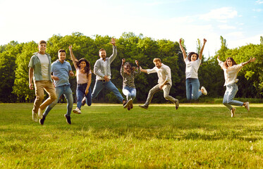 Group of a young people friends walking in the summer park. Happy diverse people girls and boys having fun, jumping outdoors. Smiling students in casual clothes spending time together.