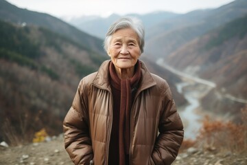 Naklejka premium Environmental portrait photography of a tender old woman wearing a sleek bomber jacket against a scenic mountain trail background. With generative AI technology