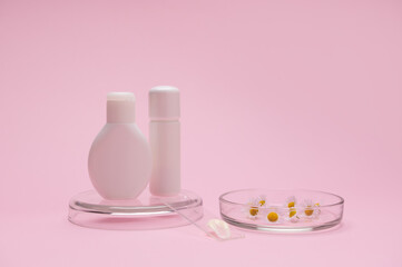Obraz na płótnie Canvas White stylish mockup bottles and smear with beauty product for skin and body care on a lab glass, Petri dish with chamomile flowers, isolated pink background. Copy advertising space. Herbal cosmetic