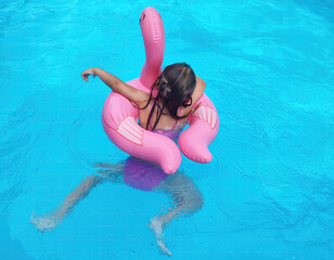 Little Girl Swimming with flamingo in a Swimming Pool