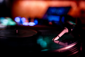 A vinyl record is seen playing spinning in a nightclub