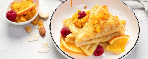 Crepe suzette with orange sauce and raspberry for a delicious breakfast.