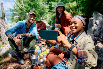 Group of happy hikers taking selfie while camping in mountains.