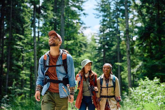 Happy backpacker and his friends hiking in forest.