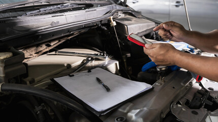 Mechanic using battery testing tool checking car battery during Car Maintenance in repair shop